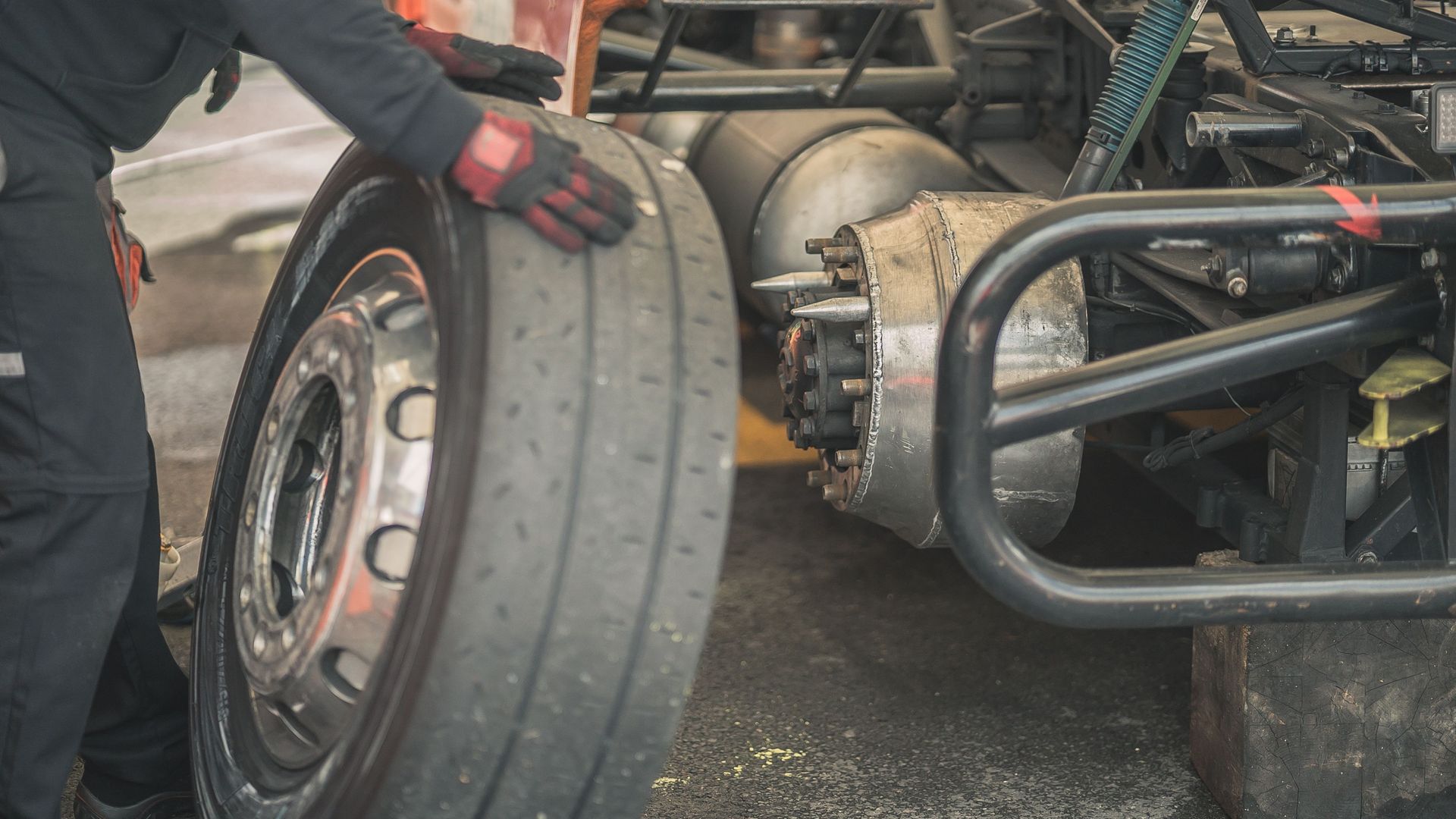 Mechanic working on replacing a tire in a professional automotive garage setting.